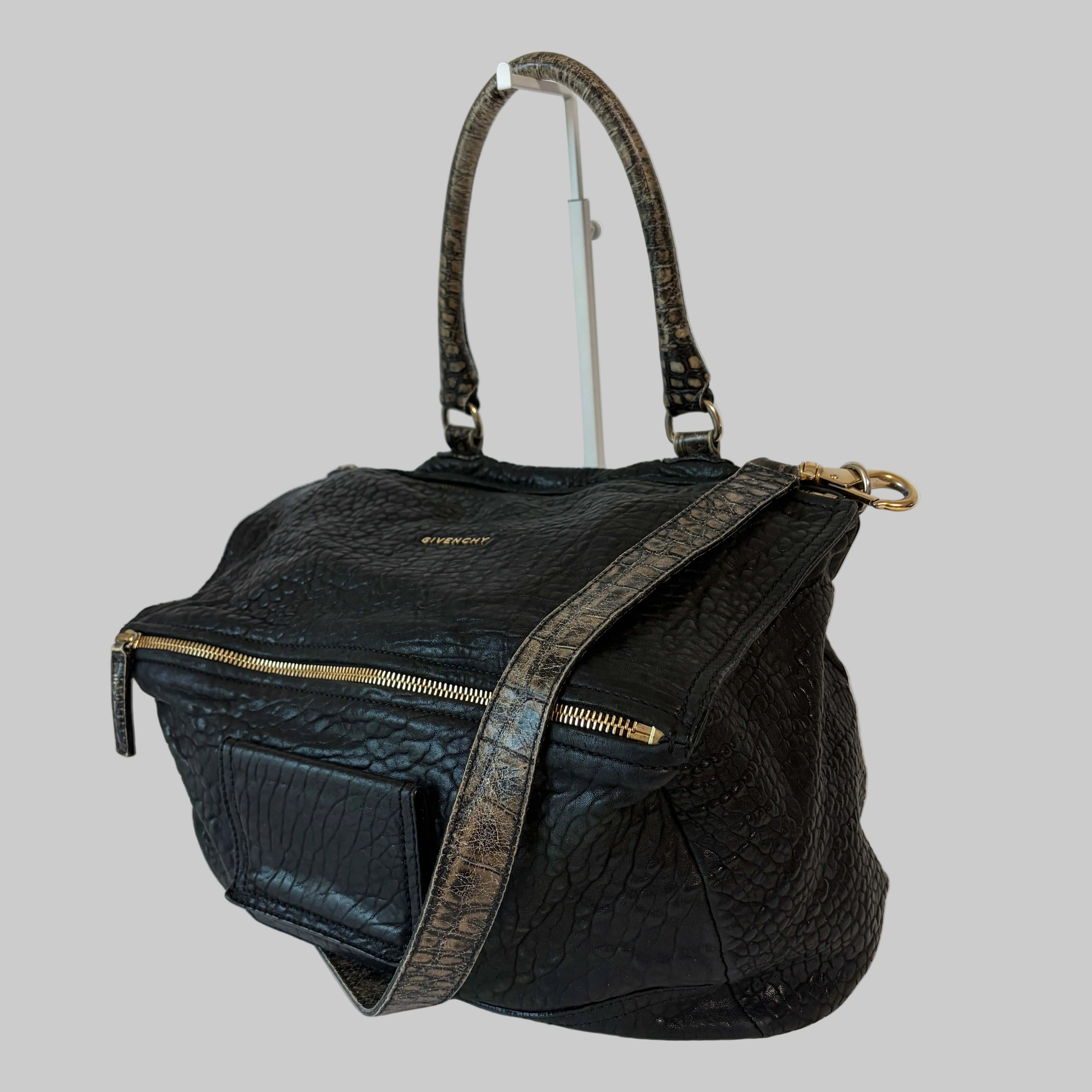 Black textured handbag with gold accents on a white background